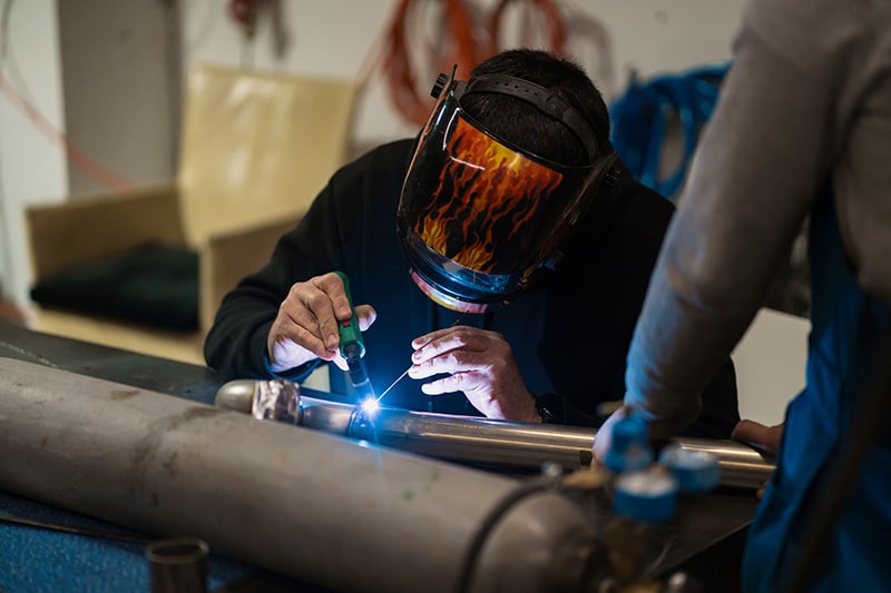 man working with argon welding machine garage